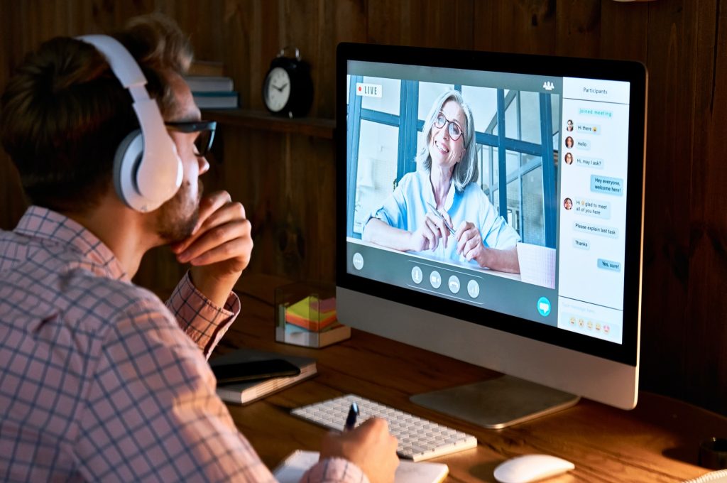 male student wearing headphones taking online course seminar watching webinar